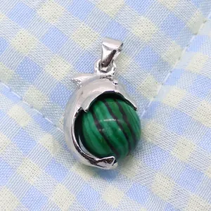 Macro detail of silver dolphin pendant holding a green striped malachite style bead