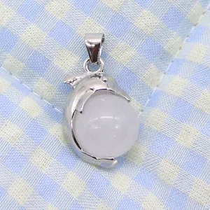 Detailed view of a silver dolphin pendant clutching a smooth white round gemstone bead