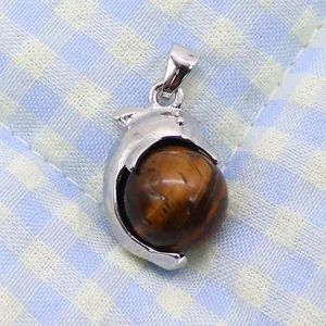 Detail of dolphin shaped silver pendant holding a polished natural tiger eye stone bead
