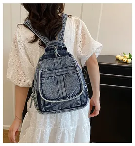 Detail view of washed blue denim backpack with front zipper pocket and retro style