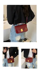 Detail of burgundy glossy patent leather handbag with gold buckle and slim strap