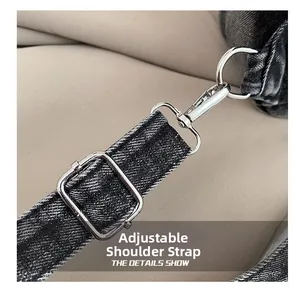 Detail view of adjustable black denim shoulder strap with silver metal buckles on backpack