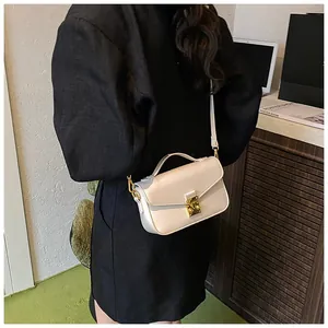 Detail of minimalist cream leather handbag with gold turn-lock and elegant top handle