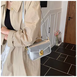 Close-up of metallic silver handbag with gold twist lock and top handle on a model