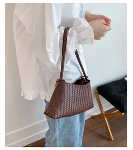 Borsa a spalla in pelle intrecciata marrone abbinata a camicia bianca e jeans blu