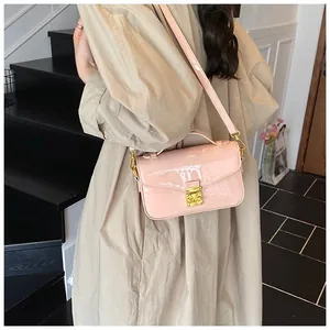 Detail of light pink patent leather crossbody bag with golden S-shaped metal lock closure