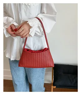 Dettaglio della borsa a spalla in pelle intrecciata bordeaux con fodera rossa