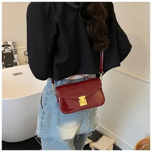 Detail of dark red patent leather handbag with gold buckle and mirror finish