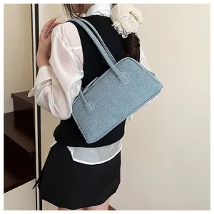 Detailed back view of a light blue denim textured shoulder bag worn with a white shirt