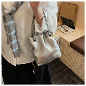 Detail of silver metallic drawstring bucket bag with chunky chain strap and logo lettering