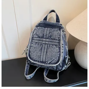 Close-up of vintage washed denim backpack featuring white stitching and flap pocket