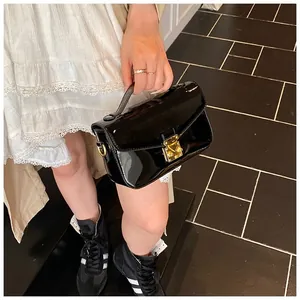 Detail of black patent leather handbag with gold metal clasp and luxury glossy texture
