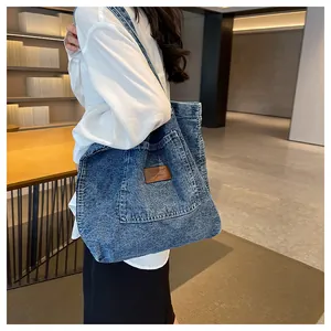 Detailed shot of washed denim tote bag featuring a leather patch on a model's shoulder