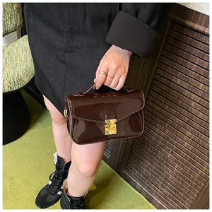 Detailed view of deep brown patent leather handbag with golden S-lock metal closure