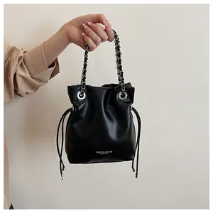 Close-up of black textured leather bucket bag with silver metal eyelets and chain strap