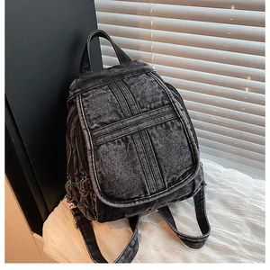 Detail shot of black washed denim backpack featuring vintage texture and front flap design