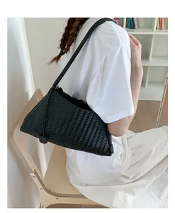 Dettaglio di borsa hobo nera intrecciata a mano con elegante tracolla stile parigino