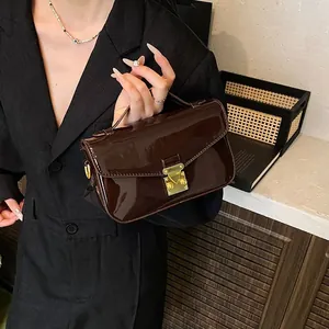 Minimalist dark brown patent leather handbag with gold triangle lock and top handle