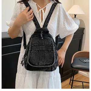 Detail shot of vintage black washed denim backpack with multiple zippers on female model