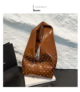 Détail d'un sac cabas marron brillant avec rivets argentés sur fond de roche blanche