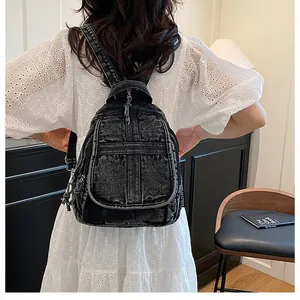 Close-up of black washed denim mini backpack on model showing vintage texture and strap