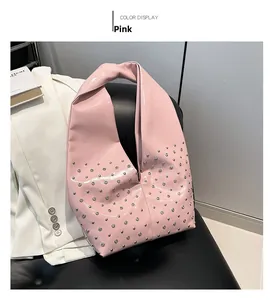 Détail d'un sac hobo en cuir rose brillant avec rivets argentés et bandoulière large