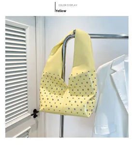 Détail du sac hobo jaune en cuir verni avec clous argentés sur cintre métal