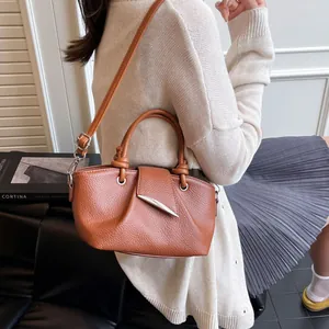 Detailed close-up of caramel brown pebble leather texture and silver buckle on bucket bag