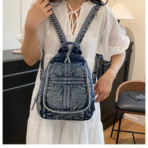 Mini vintage blue washed denim backpack on a model wearing a white lace dress