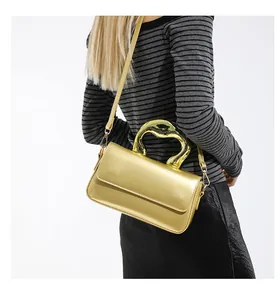 Model wearing a metallic gold shoulder bag with a unique melted gold metal handle