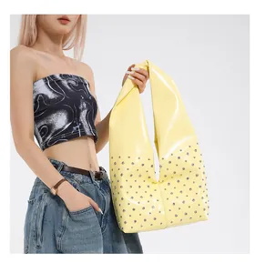 Gros plan sur le sac hobo jaune vif avec rivets argentés et finition vernie