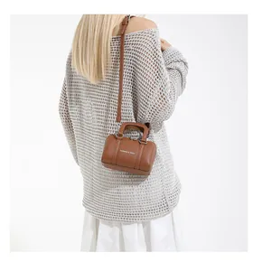 Brown mini Boston bag worn crossbody by model, featuring white lettering detail