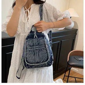 Detail of vintage blue washed denim backpack with flap and zipper pockets on a model