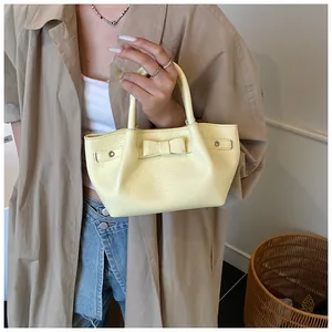 Detail of yellow lychee grain leather handbag with a 3D bow and silver metal eyelets
