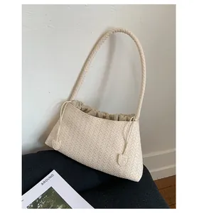 Dettaglio della trama in ecopelle intrecciata e interno con coulisse di una borsa crema