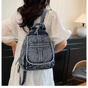 Detail of vintage acid wash denim backpack worn by a model in a casual indoor setting