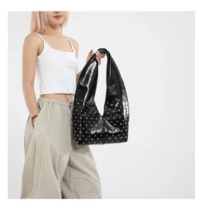 Gros plan sur un sac cabas en cuir verni noir avec des rivets argentés style punk