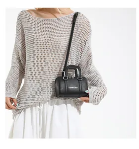 Detailed view of black mini Boston bag with lychee texture and shoulder strap on model