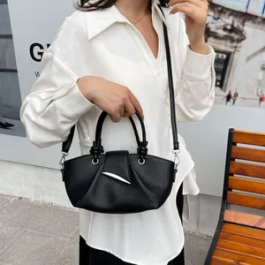 Detail of black pleated bucket bag with silver crescent buckle on white shirt background