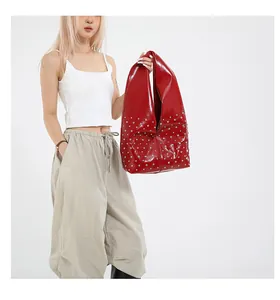 Détail du sac cabas rouge vif avec clous argentés et finition brillante sur modèle