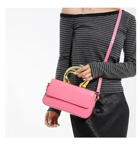 Close-up of bright pink patent leather handbag with unique gold metal sculptural handle