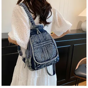 Detailed back view of a vintage washed denim backpack with multiple zipper pockets