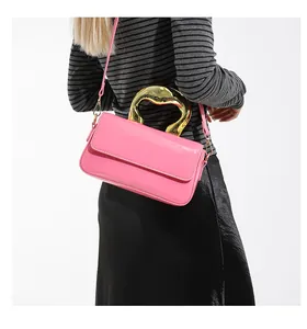 Side view of hot pink patent leather shoulder bag with a sleek gold metal handle