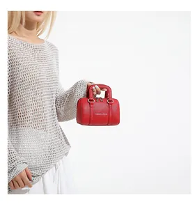 Close-up of red pebbled leather Boston bag with dual zippers and gold lettering detail