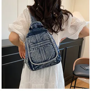 Detail of washed denim backpack with white contrast stitching and side woven brand tag