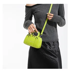 Close-up of neon green mini Boston bag with silver lettering and metallic buckles
