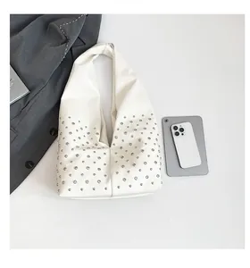 Vue à plat du sac hobo crème à rivets montrant sa grande capacité pour appareils numériques