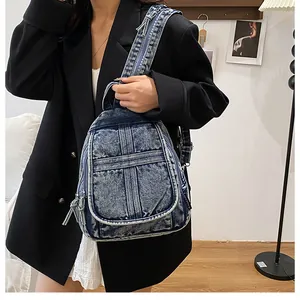 Detail of vintage washed blue denim backpack featuring cross stitching and metal zippers