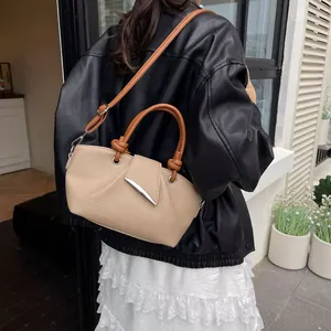 Retro beige leather bucket bag with caramel handle shown on model in urban setting