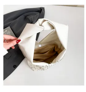 Détail du sac cabas en cuir blanc avec rivets argentés et fermeture magnétique